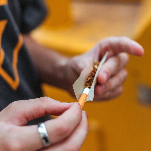 anonymous guy rolling up joint on street