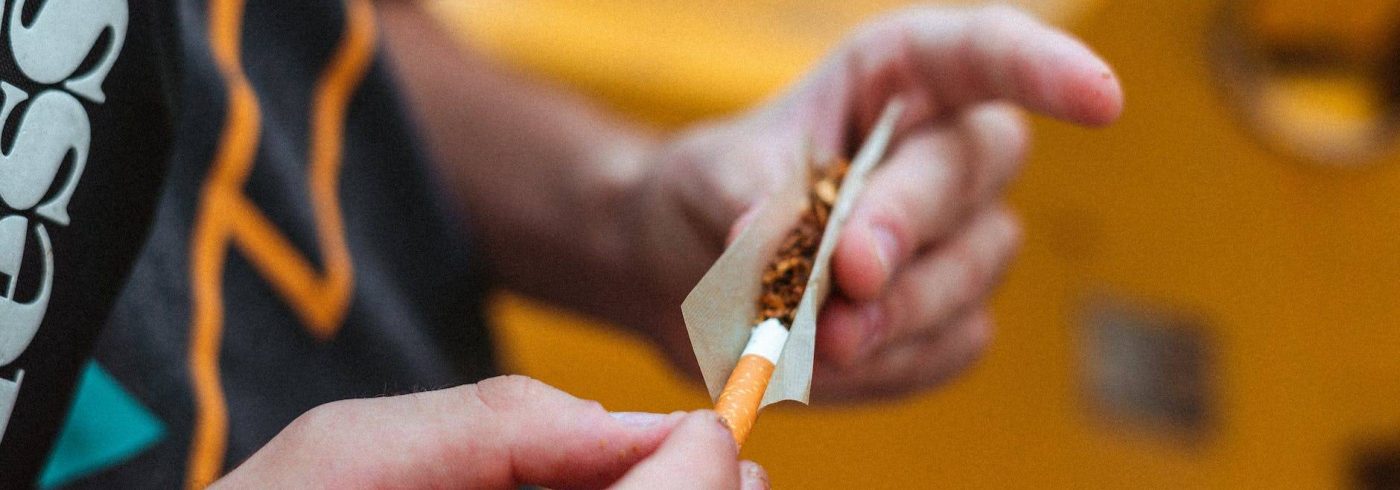 anonymous guy rolling up joint on street